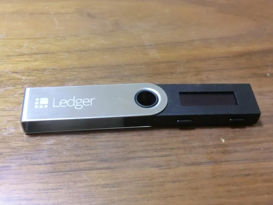 File photo: a Ledger Nano S hardware wallet on a wooden table, contextual image for the Ledger reseller investigation