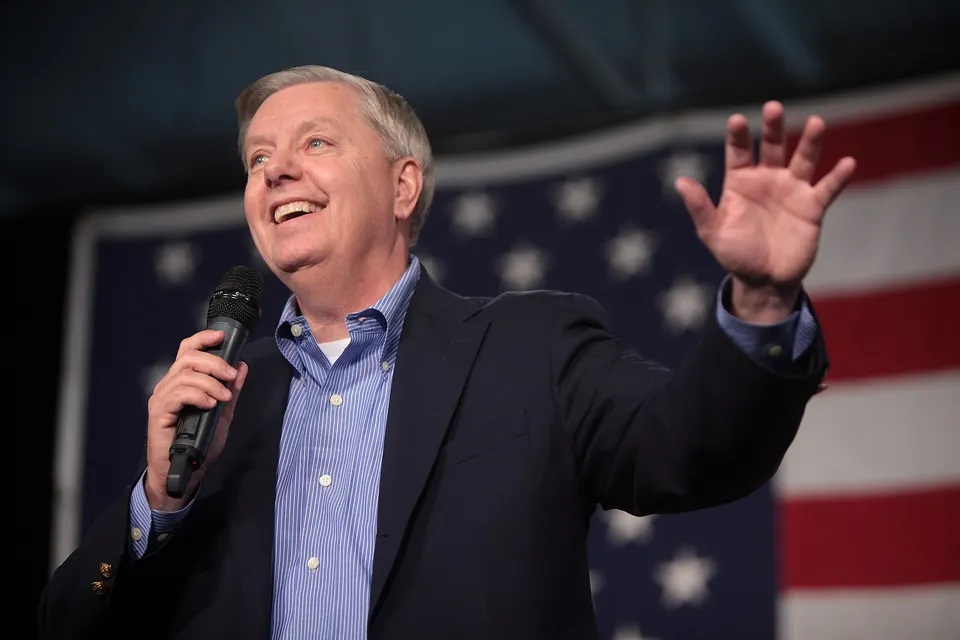 File photo of Senator Lindsey Graham, for whom the Russia sanctions law is named, speaking at a microphone in front of an American flag
